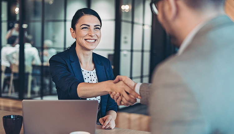 Businesswoman Shaking Hands During a Job Interview. Calculating Your Worth During a Security Job Search.