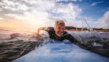 Senior Man Riding a Surfboard. Security Career Exit Strategies.