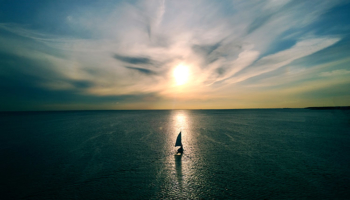 Small sailboat floating towards the horizon at sunset. A Visionary Plan for Uncharted Waters.